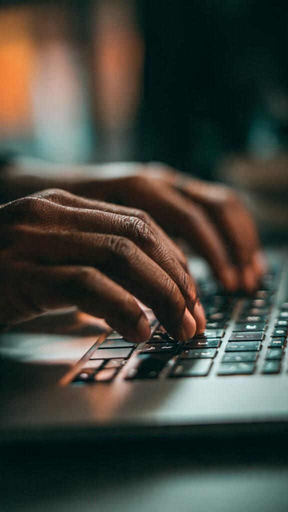  Close-up of hands typing on a laptop keyboard to write prompts for an AI tool