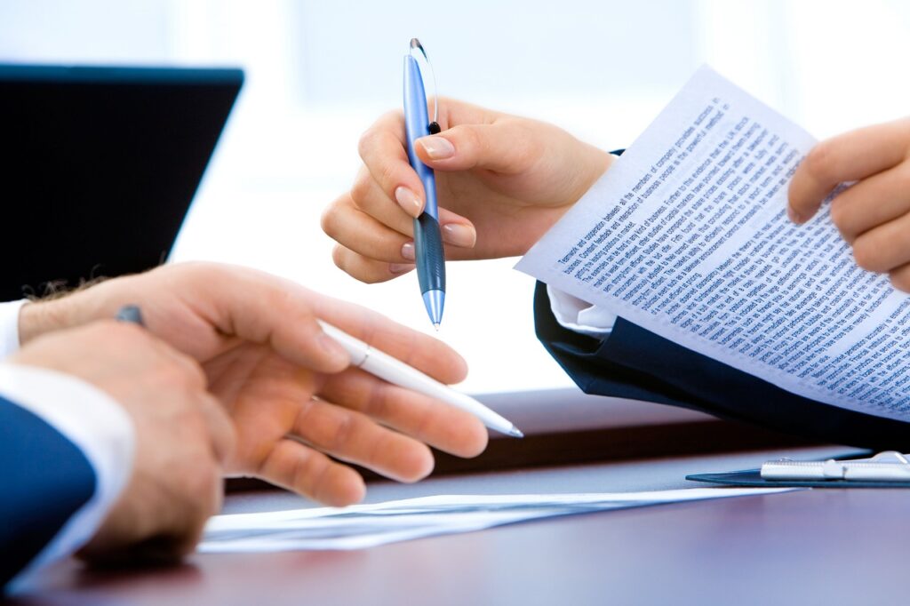  Person organizing important documents on a desk next to a laptop