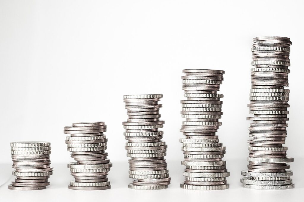 Person holding a takeaway coffee beside a small pile of coins, symbolizing cutting daily expenses