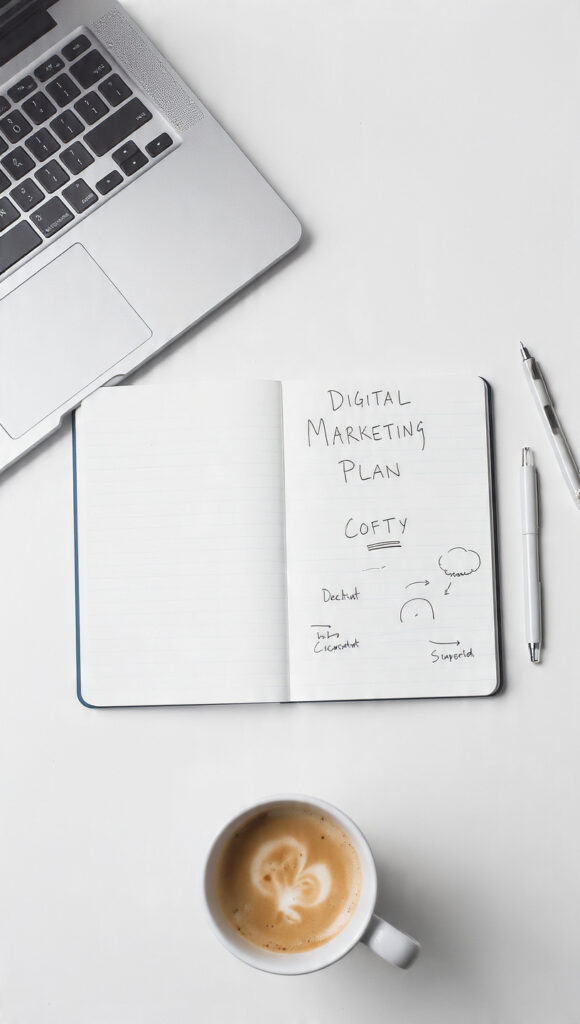  Notebook labeled digital marketing plan on a desk with a laptop and coffee cup
